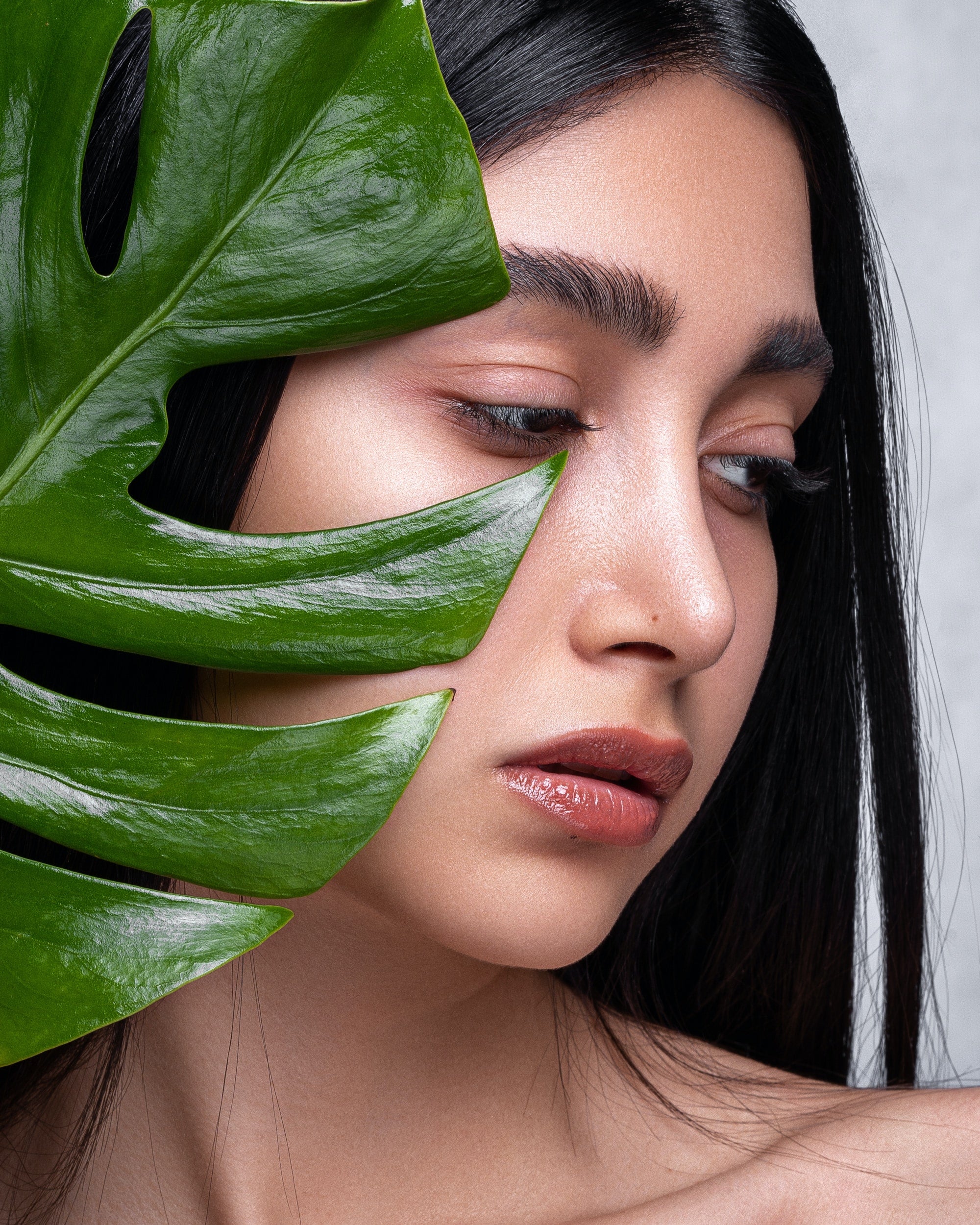 A woman with clean skin holding a tropical plant